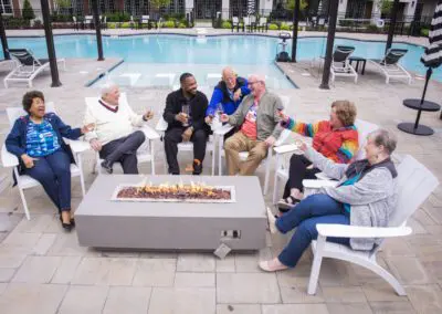 Friends having a toast outdoors by a pool and firepit